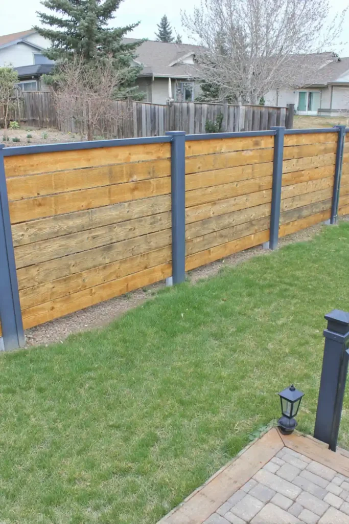 33 Privacy Fence Ideas That Make Your Yard Feel More Peaceful 4 Stained wood privacy fence panels with contrasting black posts in a modern backyard
