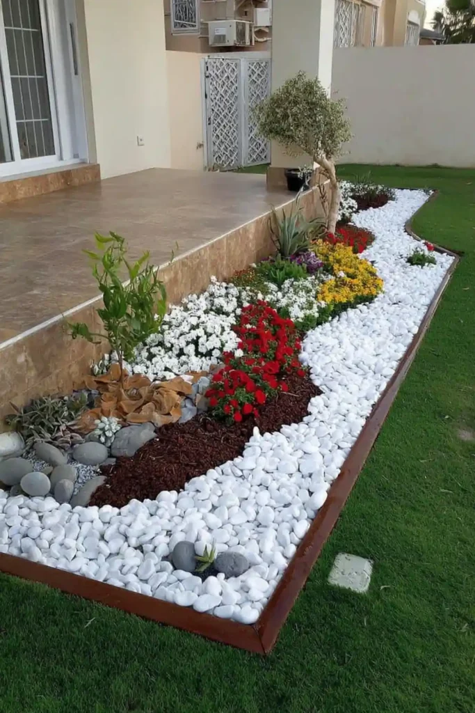 Flower bed with white pebbles and colorful flowers creating a clean and defined garden area