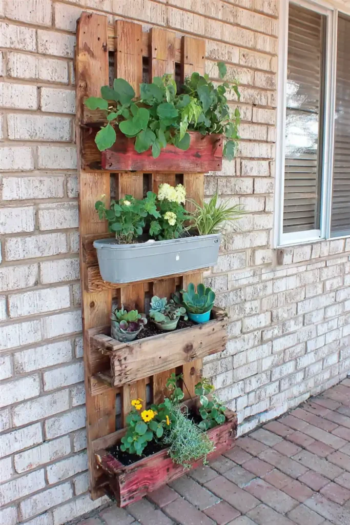 Easy DIY vertical pallet garden with gray planters against a light brick wall