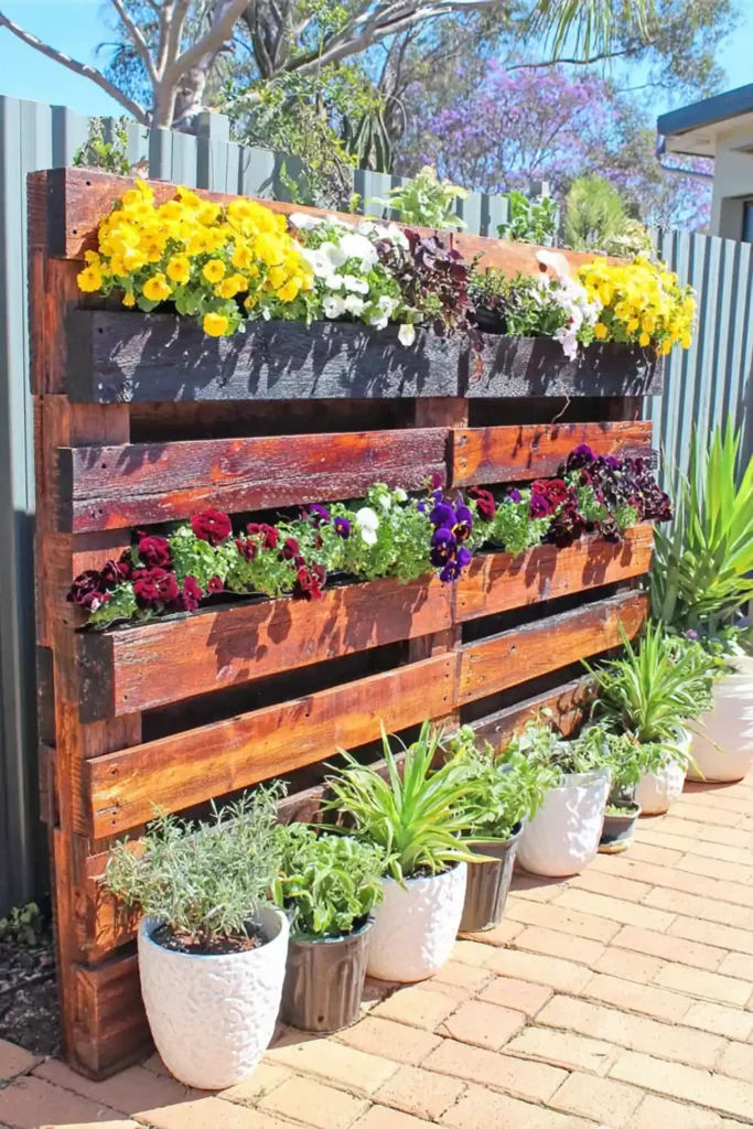 Rustic vertical pallet garden with mixed flowers and greenery in horizontal pockets