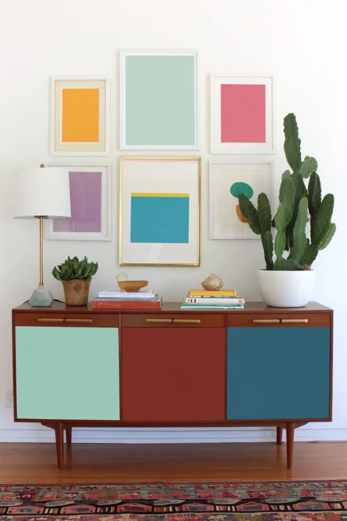 Brown credenza with three uneven vertical columns of framed art in a stacked gallery wall layout.