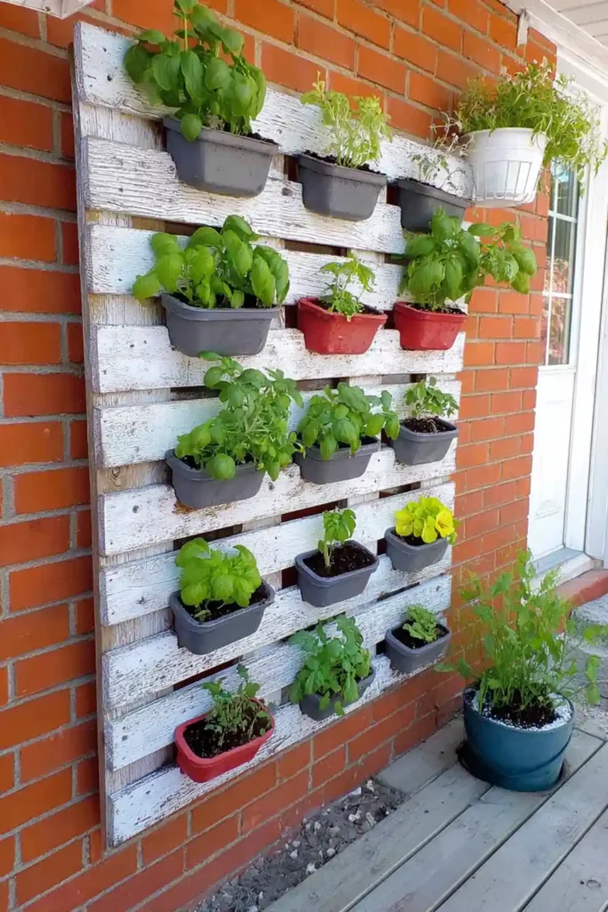 Wall-mounted pallet herb garden with black planter boxes on white boards