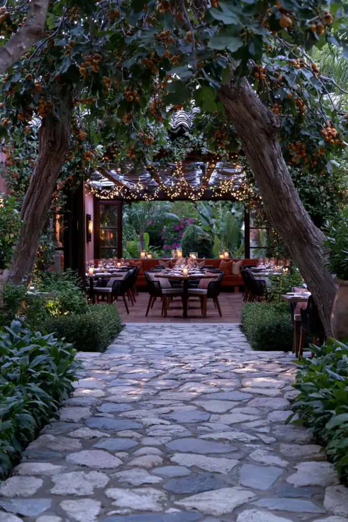 Stunning Garden Walkway Layout Ideas for a Beautiful Outdoor Path 24 Bistro garden walkway with a stone path, vine-covered overhead structure, small dining tables, chairs, and candlelight.