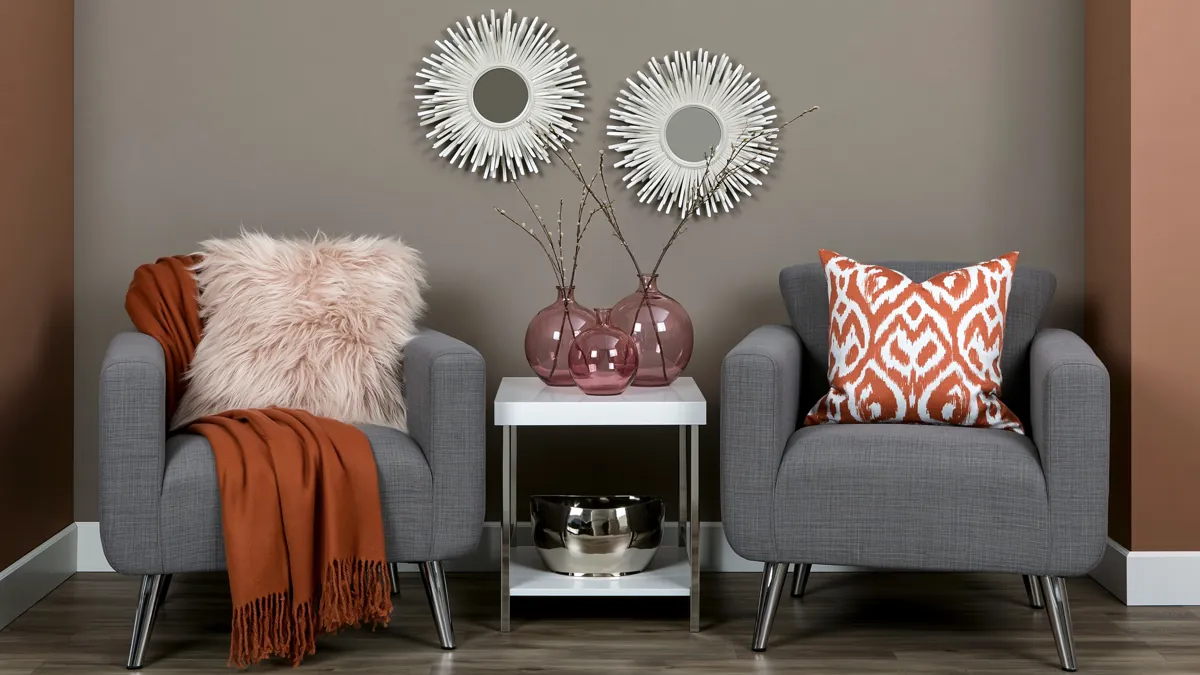 Trend Color Spotlight: Off the Grid Paint Inspiration for Warm, Modern Rooms 1 Warm beige-gray sitting area with gray chairs, orange accents, white side table, sunburst mirrors, and soft Off the Grid paint inspiration.