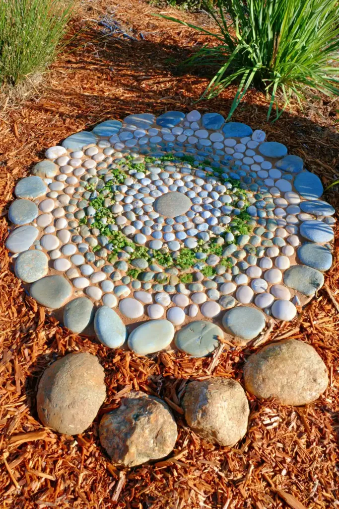 20 Budget-Friendly Outdoor Landscaping Ideas for a Charming Yard 12 Round pebble mosaic stepping stone set into brown mulch along a garden path.