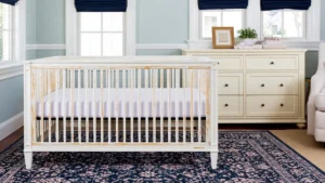 Transitional nursery design ideas with a convertible crib, cream dresser, glider, navy rug, and soft blue walls