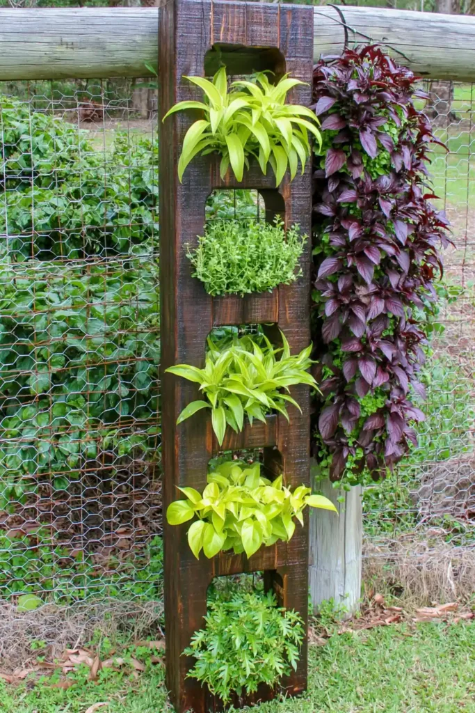 20 Budget-Friendly Outdoor Landscaping Ideas for a Charming Yard 8 Vertical garden planter column with bright green plants growing against outdoor fencing.