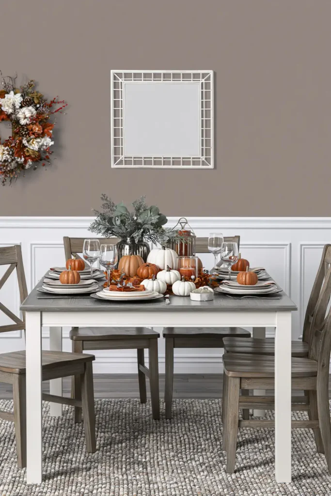 Trend Color Spotlight: Off the Grid Paint Inspiration for Warm, Modern Rooms 5 Warm greige dining room with seasonal table decor, wooden chairs, white wainscoting, and soft neutral walls.