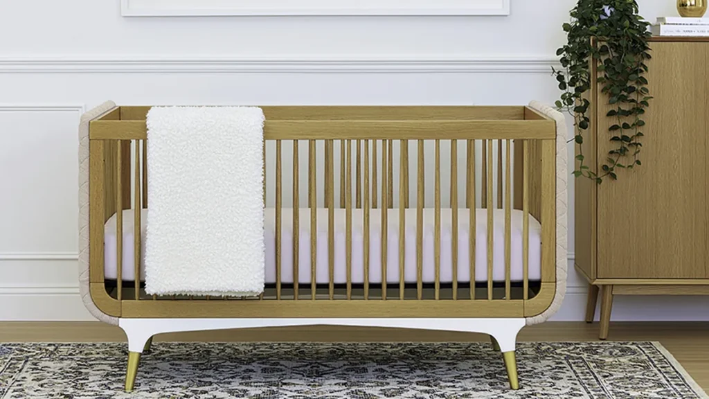 Wooden crib with white blanket and natural nursery storage for a room that grows over time
