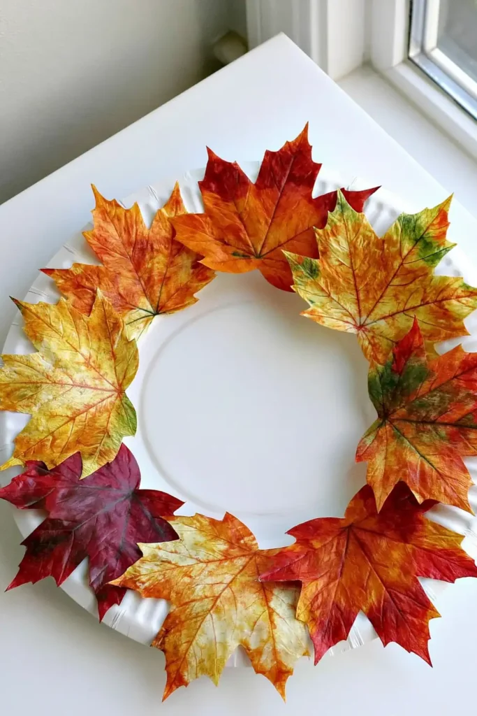 DIY Fall Leaf Crafts Decor Ideas for Cozy Autumn Home Styling 17 DIY magnolia wreath with layered green leaves and brown undersides hanging on a blue paneled door.