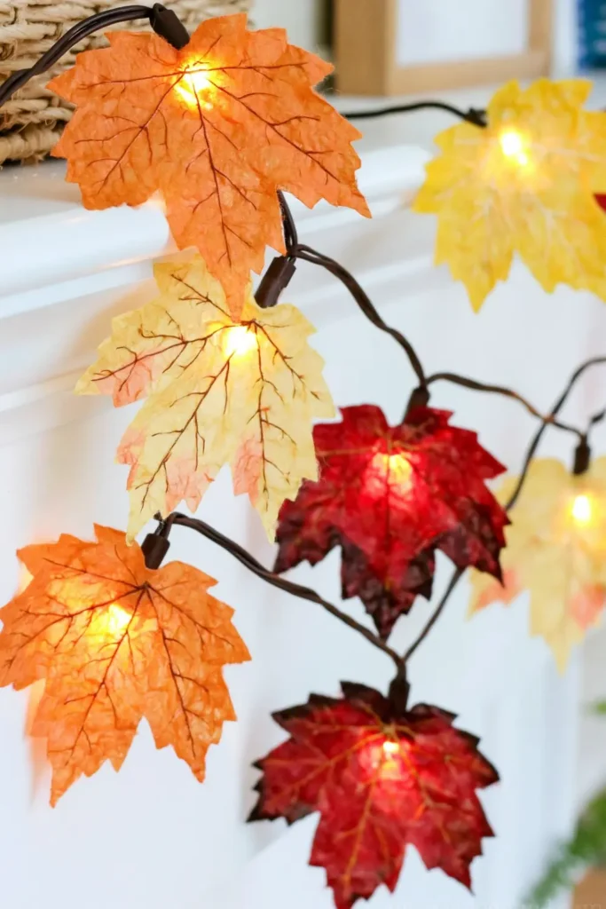 Paper plate fall wreath with yellow, orange, and red leaves attached around a white wreath base.