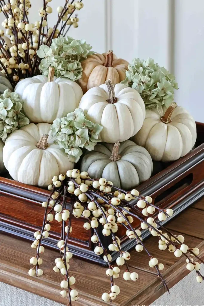 31 Fall Table Decor Ideas for Entertaining in a Warm, Seasonal Style 18 White, ivory, and pale gray pumpkins arranged with dried green hydrangeas and cream berries in a dark wooden tray.