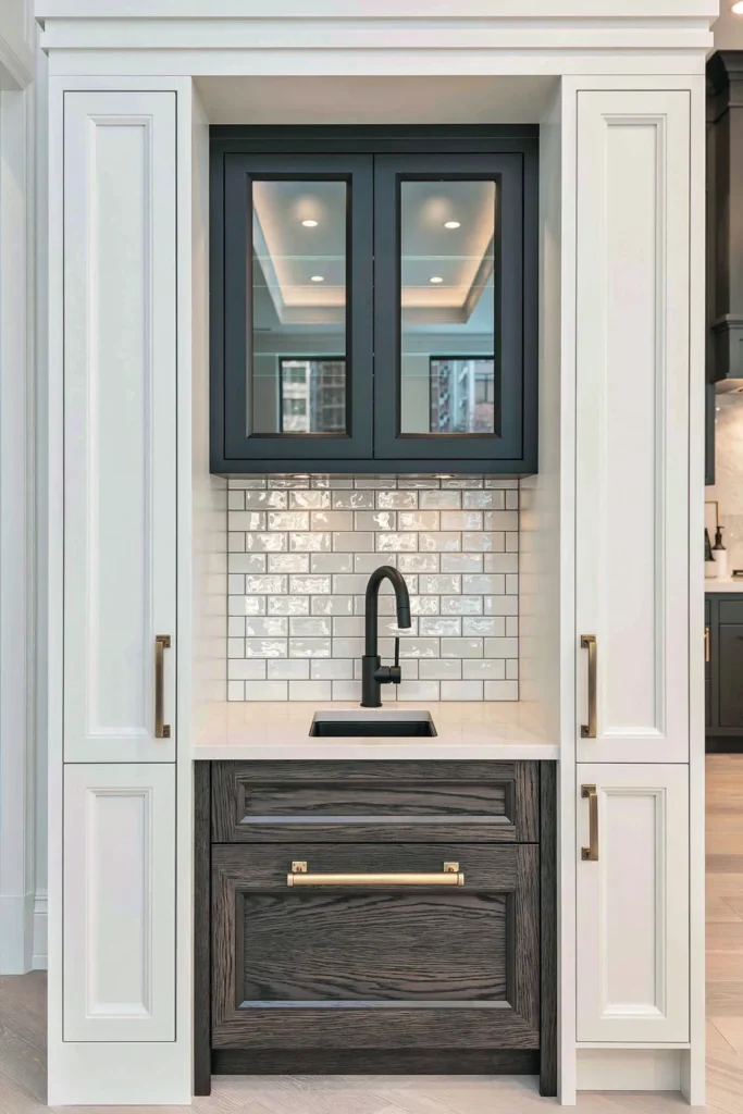 Glossy white subway tile backsplash in a built-in beverage niche with dark cabinets and brass hardware.