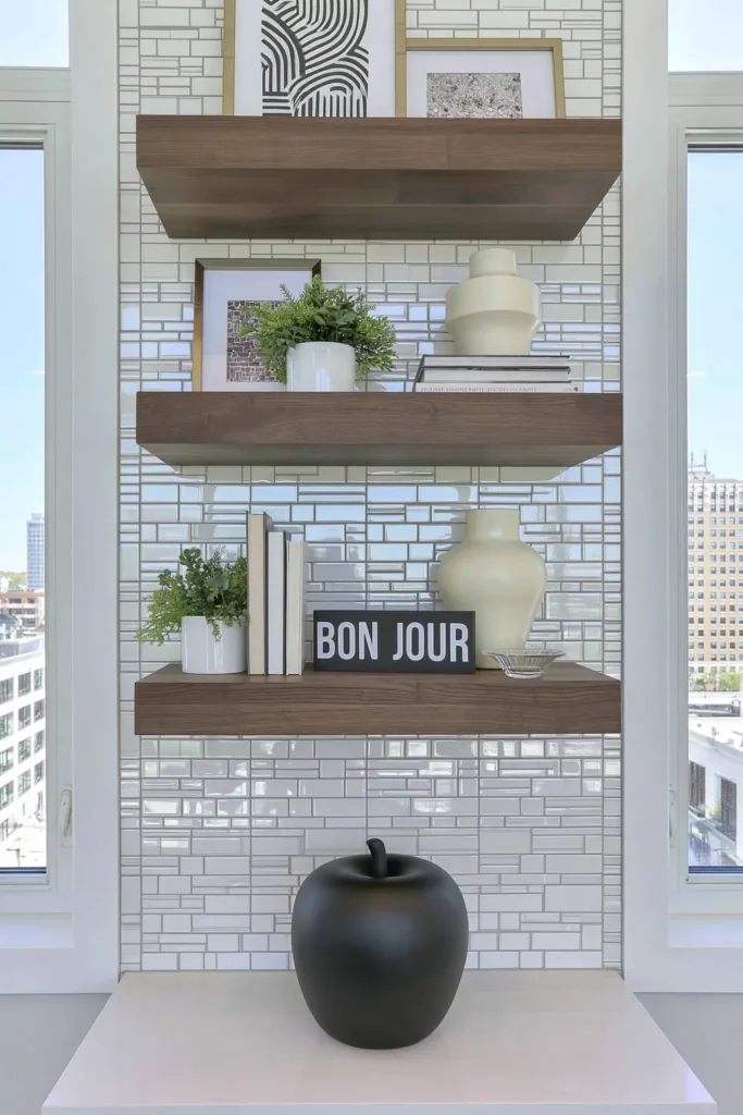 Dark wood floating shelves styled with plants and decor on a glossy white subway tile backsplash.