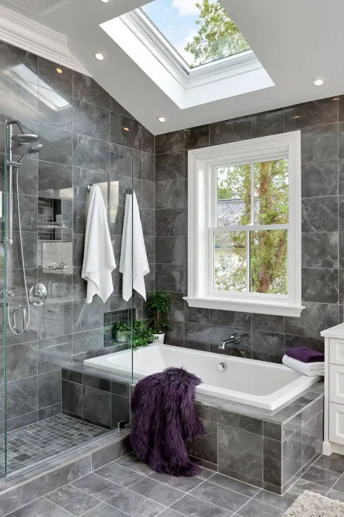 Bathroom Color Schemes That Never Go Out of Style 5 Monochromatic gray bathroom color scheme with dark tile, bathtub, glass shower partition, chrome fixtures, and small plant