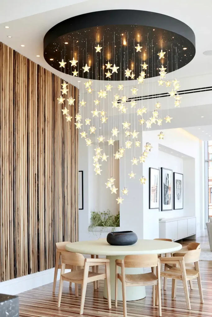 Dining Room Lighting Ideas to Create the Perfect Mood 3 Magical dining corner with star-like glass lights suspended at varied heights above a round pale table and wooden chairs.