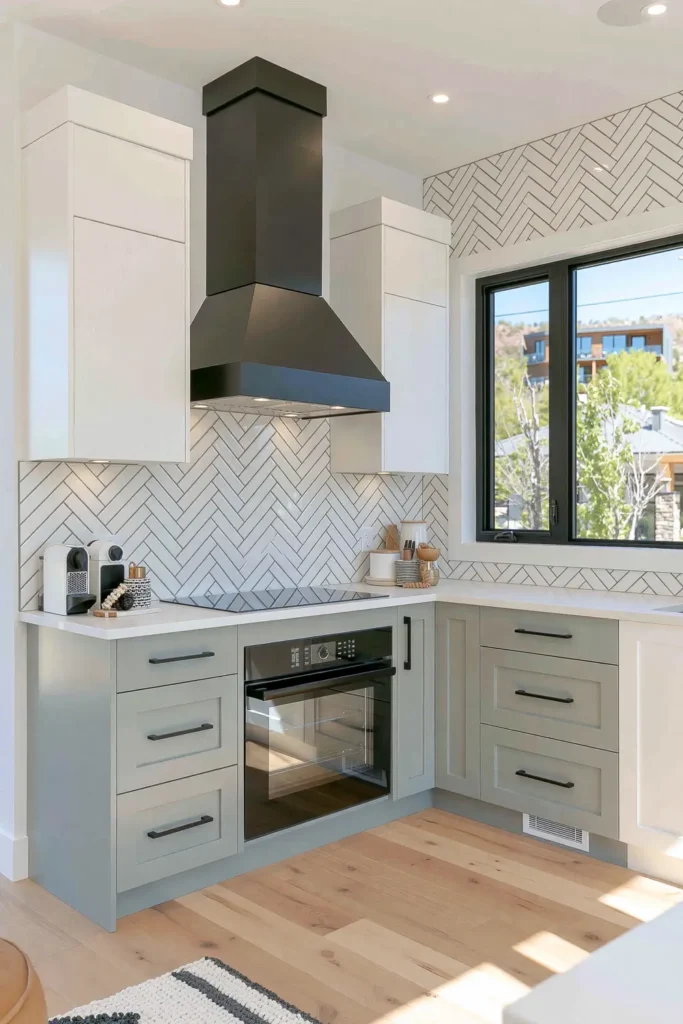 Narrow white herringbone backsplash tile behind a black range hood in a bright gray-and-white kitchen.
