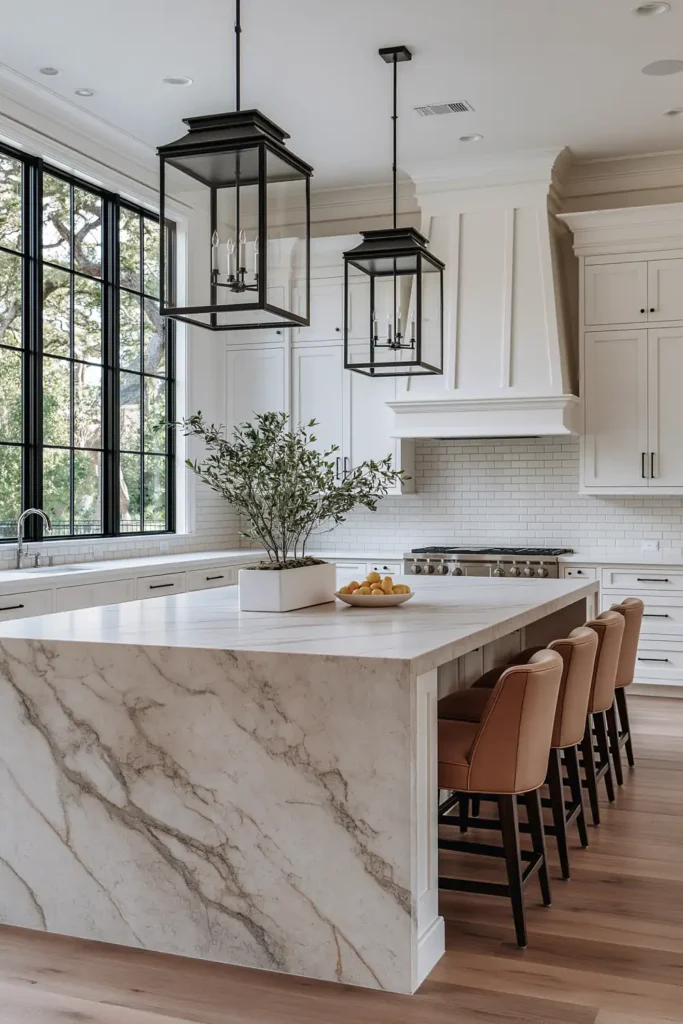 29 Barndominium Kitchen Designs for Rustic, Modern, and Timeless Spaces 6 Classic white barndominium kitchen with a veined stone island, shaker cabinets, black lantern pendants, tan stools, and tall black-grid windows.