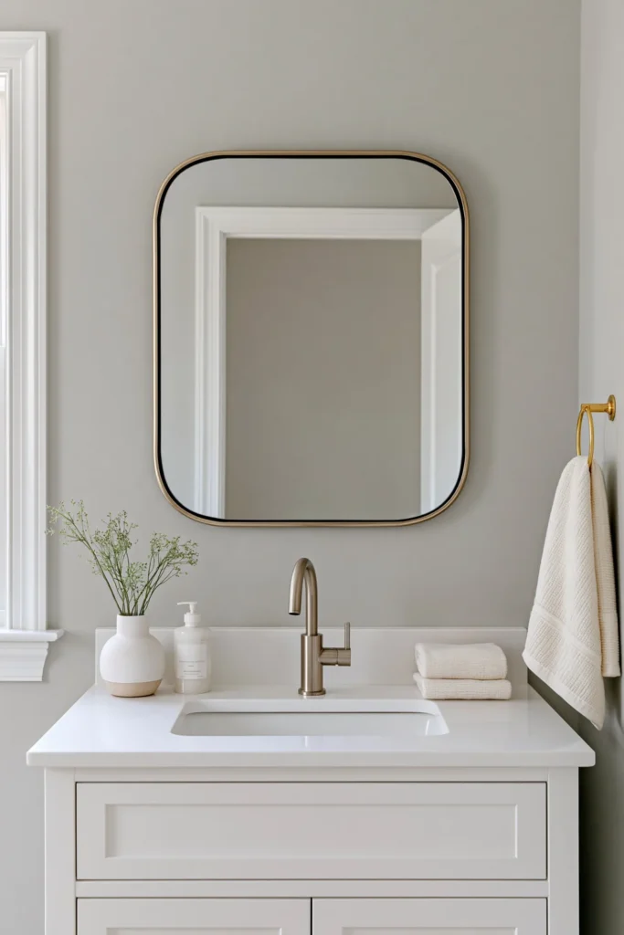 21 Guest Bathroom Decorating Ideas for a Friendly Space 8 Bright guest bathroom with pale blue-gray walls, a white vanity, gold fixtures, and calm neutral decor.