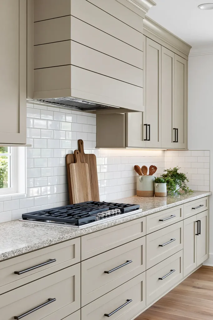 29 Neutral Kitchen Cabinet Ideas for a Calm, Timeless Kitchen 14 Warm beige shaker kitchen cabinets with a paneled range hood, speckled granite counters, white subway tile, and dark pulls.
