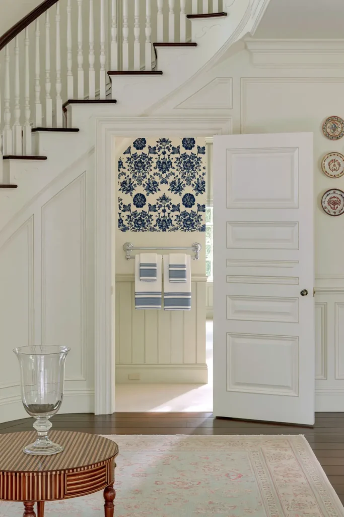 18 Secret Door Ideas That Fit Beautifully Into Your Home 13 Curved white paneled secret door under a staircase opening into a powder room with blue floral walls.