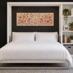 White DIY Murphy bed open against a black accent wall with built-in shelving, white bedding, plants, books, and warm-toned artwork.