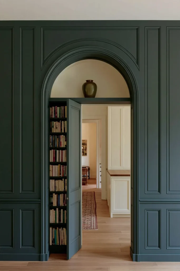 18 Secret Door Ideas That Fit Beautifully Into Your Home 6 Teal arched bookcase secret door opening into a narrow room with warm wood flooring and cream cabinetry.